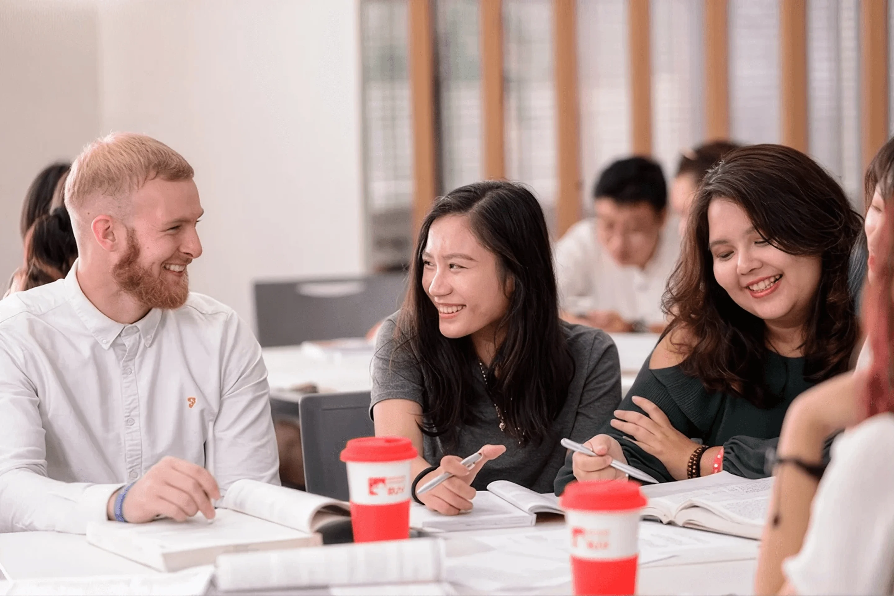 A diverse group of smiling students having a discussion around a study table.