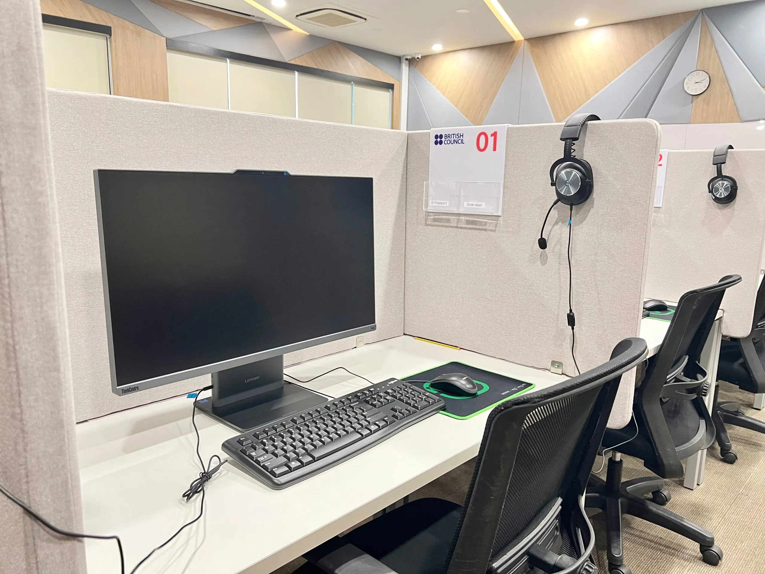 Computer workstation in a modern university lab, with a large monitor, keyboard, mouse, and headphones at an individual study desk.