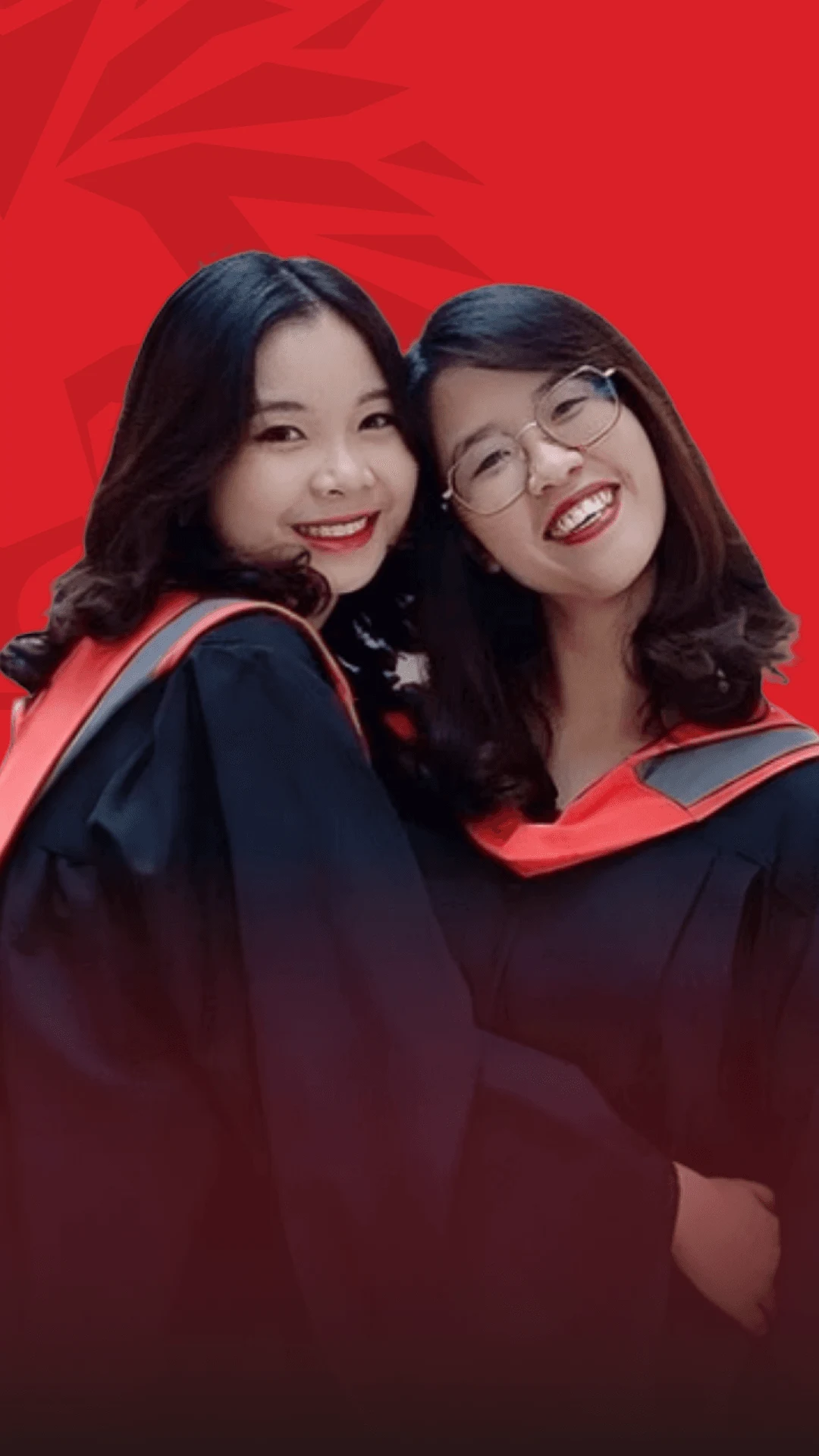 Two smiling female alumni pose for a photo, wearing graduation gowns and caps, against a red background.