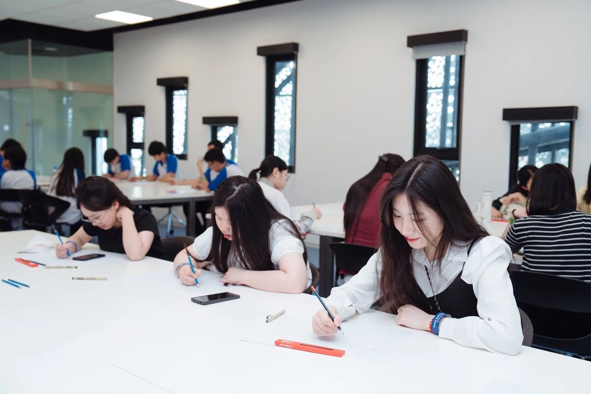 BUV students work independently on a written classroom activity at shared tables in a bright, modern learning space.