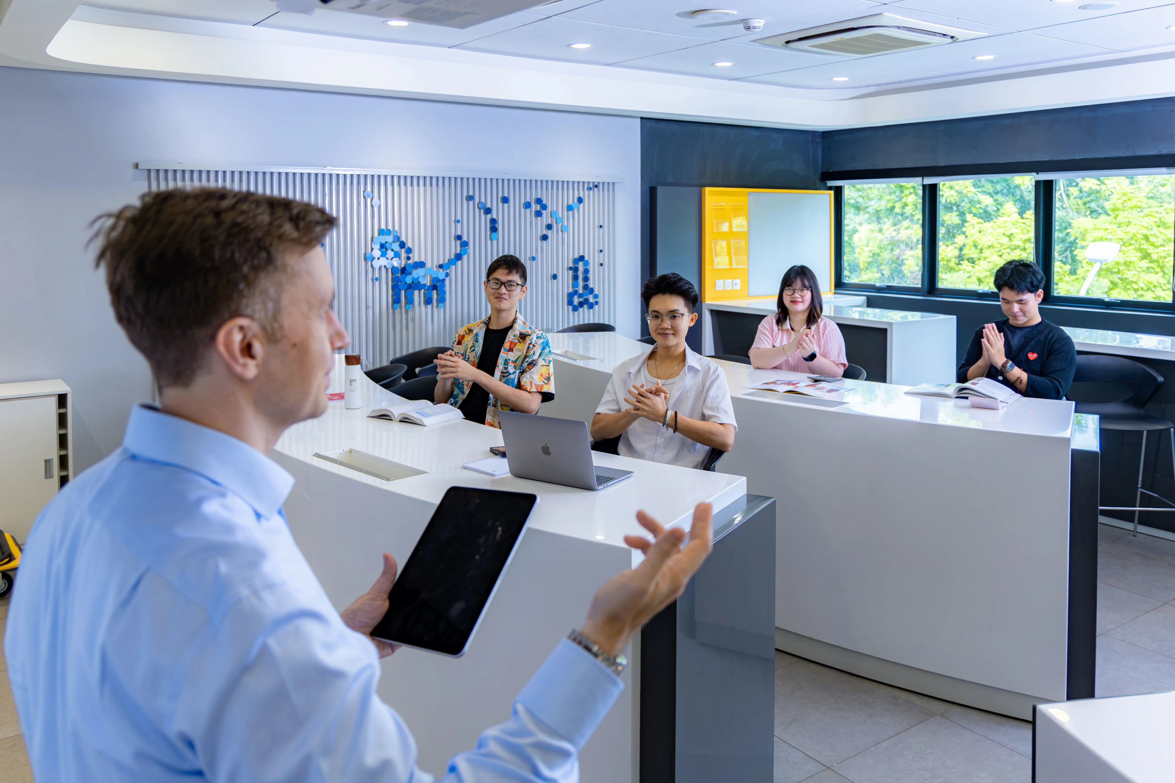 Lecturer teaching BUV students with a tablet in a modern British University Vietnam classroom