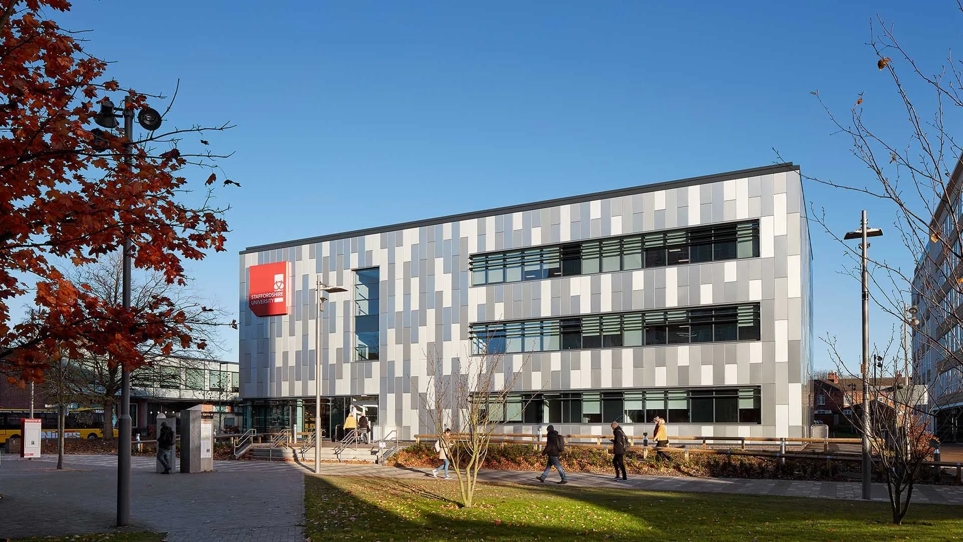 Modern University of Staffordshire campus building with a grey patterned façade under a clear blue sky.