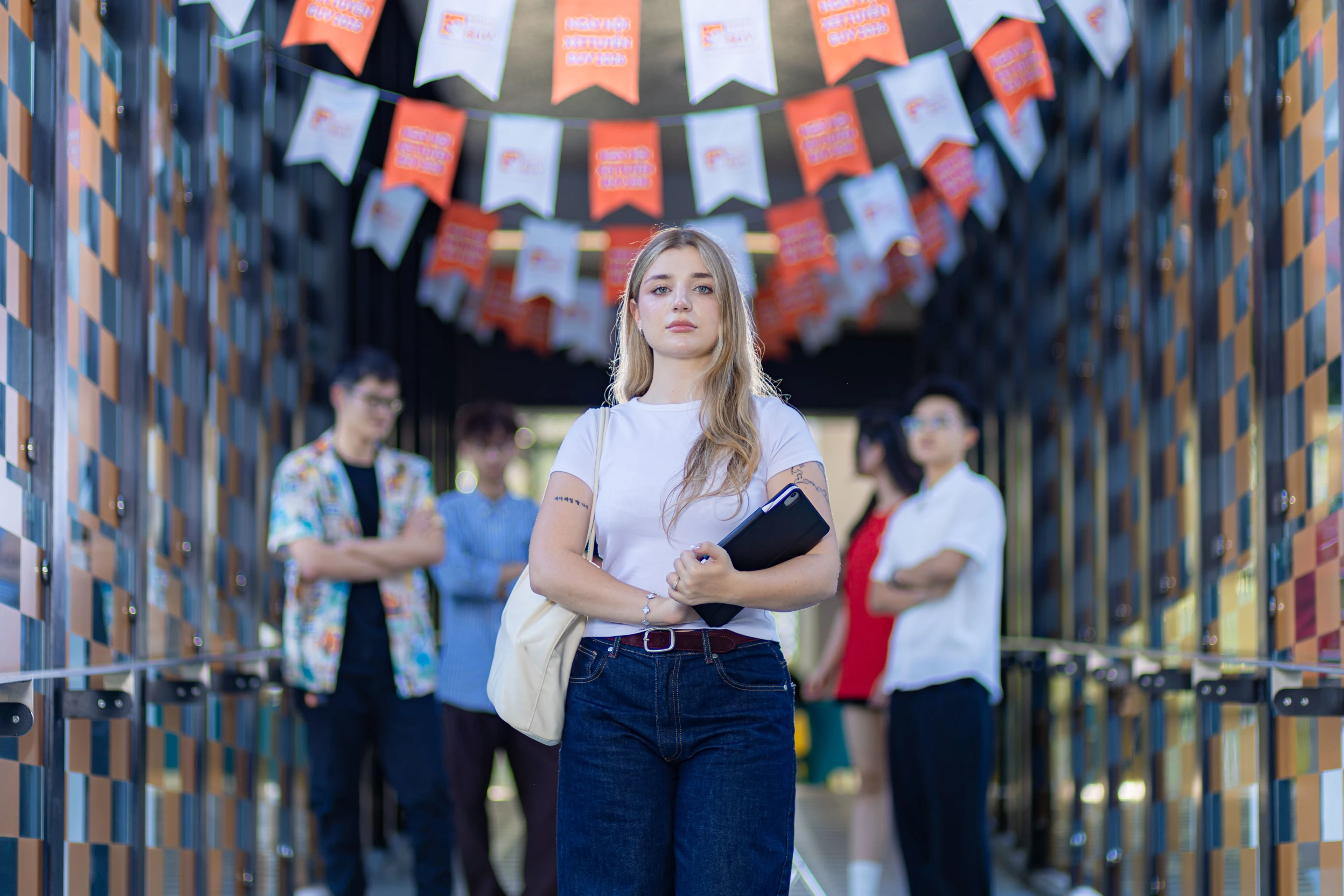 International student holding a tablet with classmates in a colorful corridor at British University Vietnam