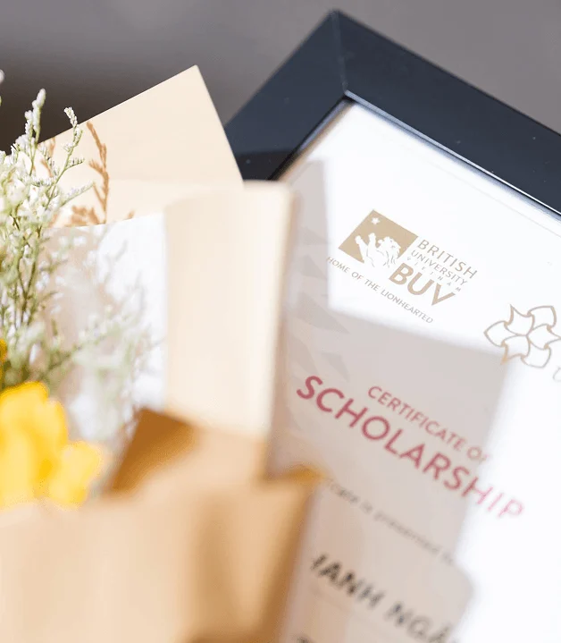 A BUV scholarship certificate displaying the words “Certificate of Scholarship,” partially covered by an open card and flowers.