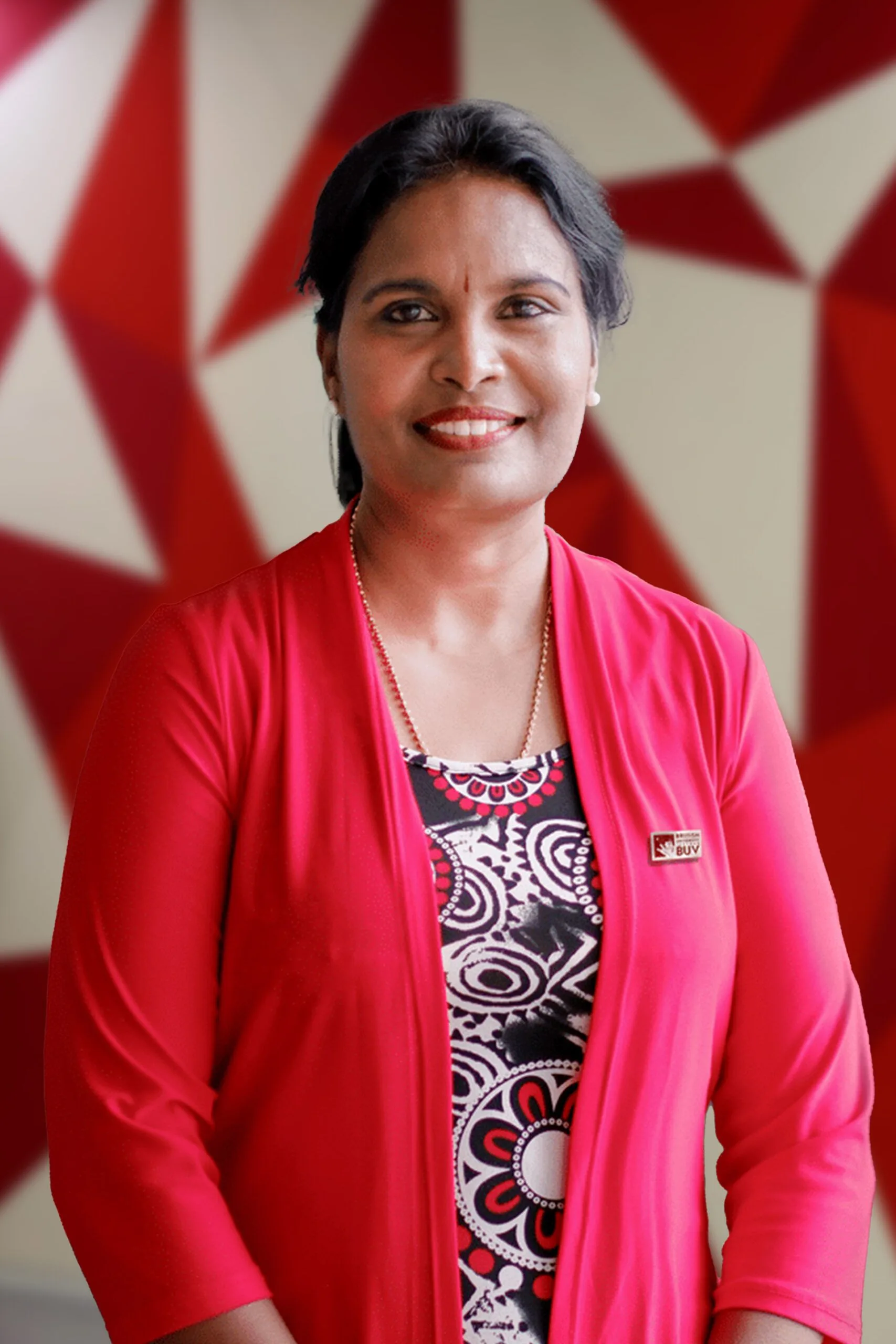 Dr Kumarashvari wearing a red cardigan and BUV badge at British University Vietnam