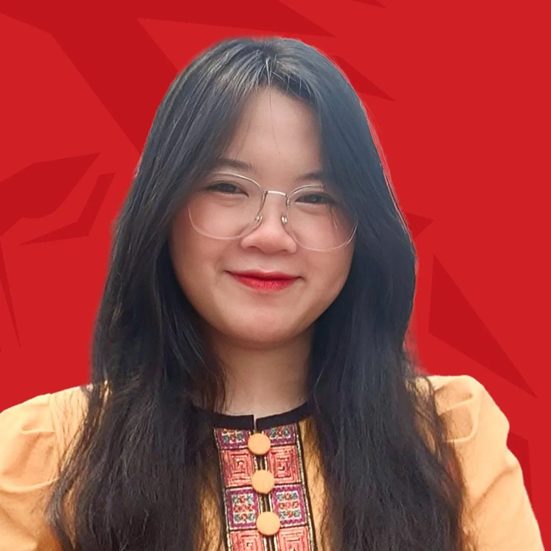 Portrait of BUV alumna Quỳnh Anh wearing glasses and a traditional embroidered outfit against a red background.