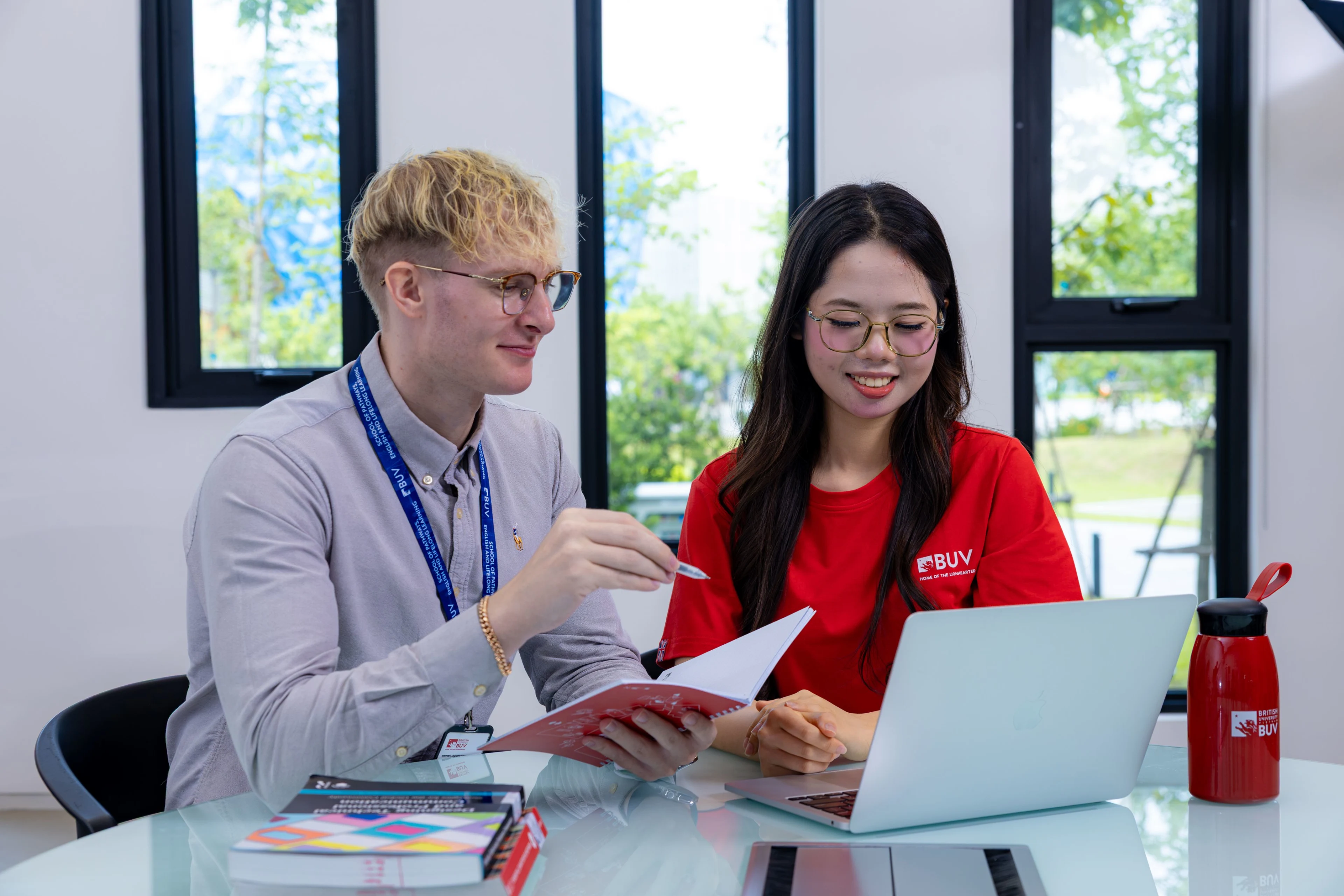 Giảng viên quốc tế hướng dẫn sinh viên tại British University Vietnam với tài liệu và laptop