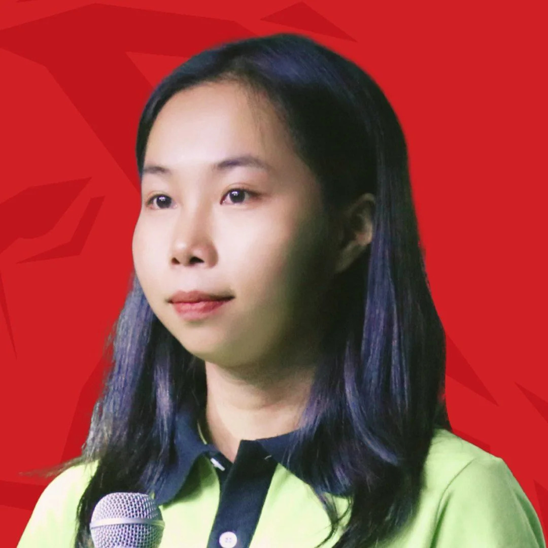 BUV alumna Oanh Nguyen speaking into a microphone against a red background.