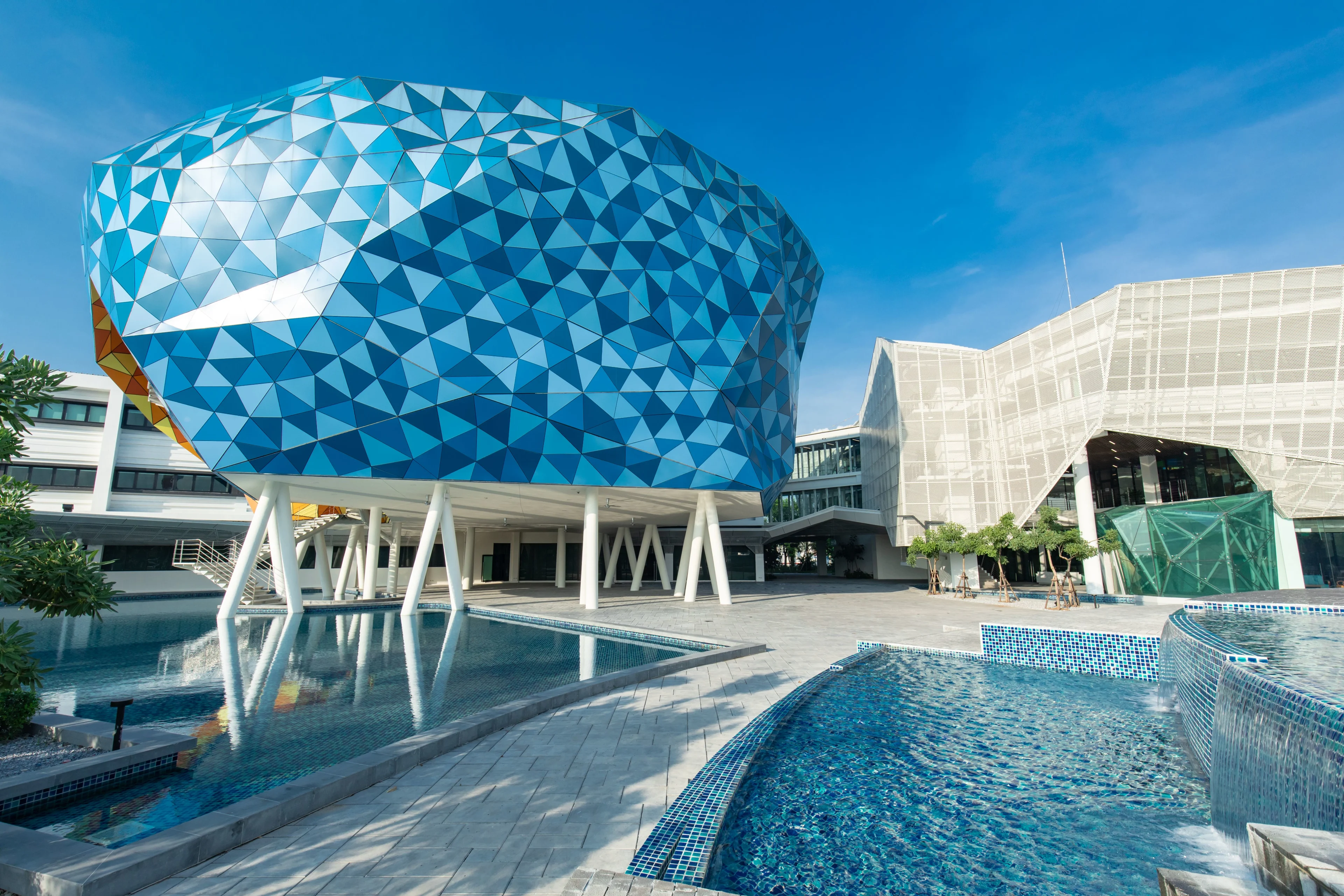 Modern BUV campus building with a blue geometric dome, reflecting pools, and a bright blue sky.