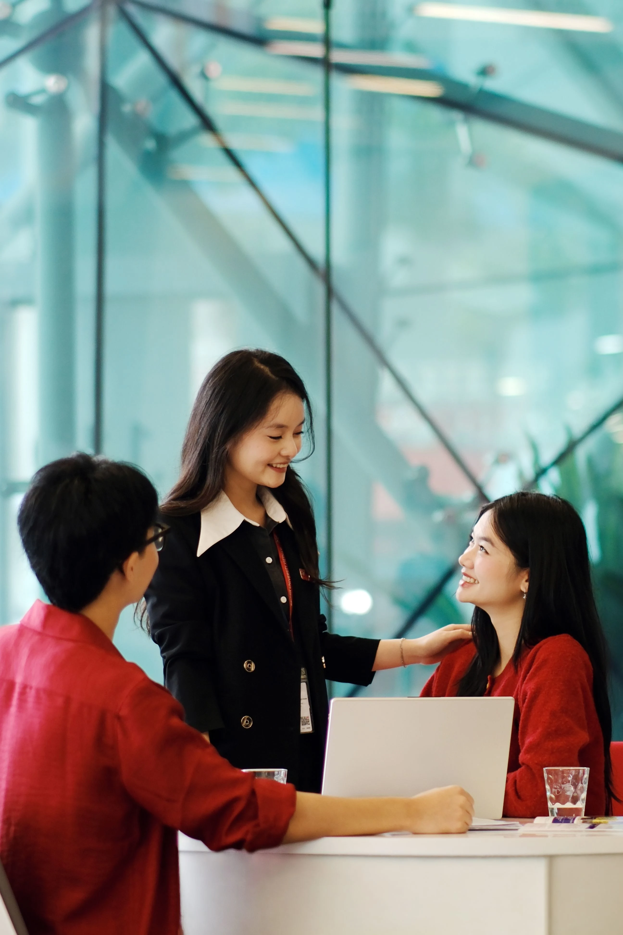 BUV students collaborating around a laptop in a modern university campus interior.