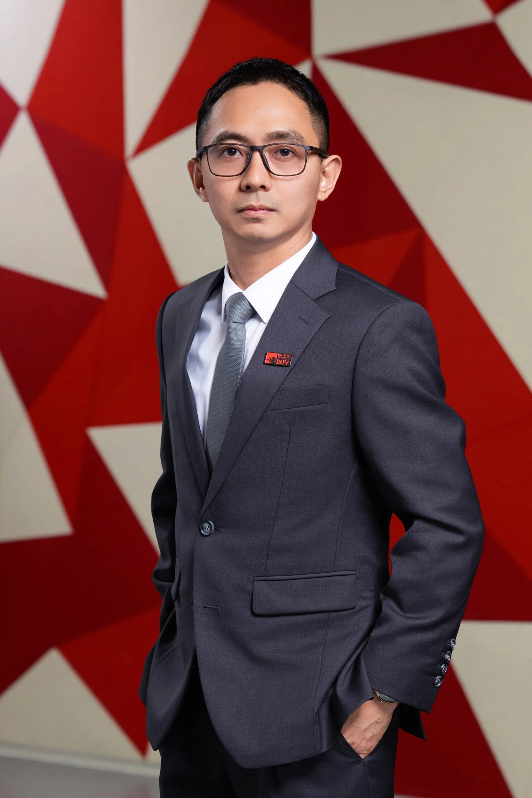 Dr. Donie Jardeleza in a grey suit with a British University Vietnam badge at BUV campus