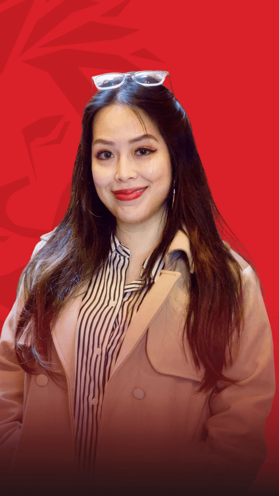 A portrait of a smiling BUV alumna wearing graduation-style accessories, against a red background.