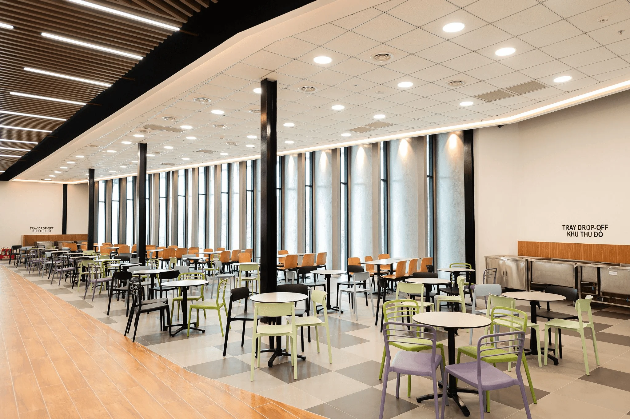 BUV campus cafeteria with colorful tables, chairs, and tray drop-off area labeled “Khu Thu Đồ”