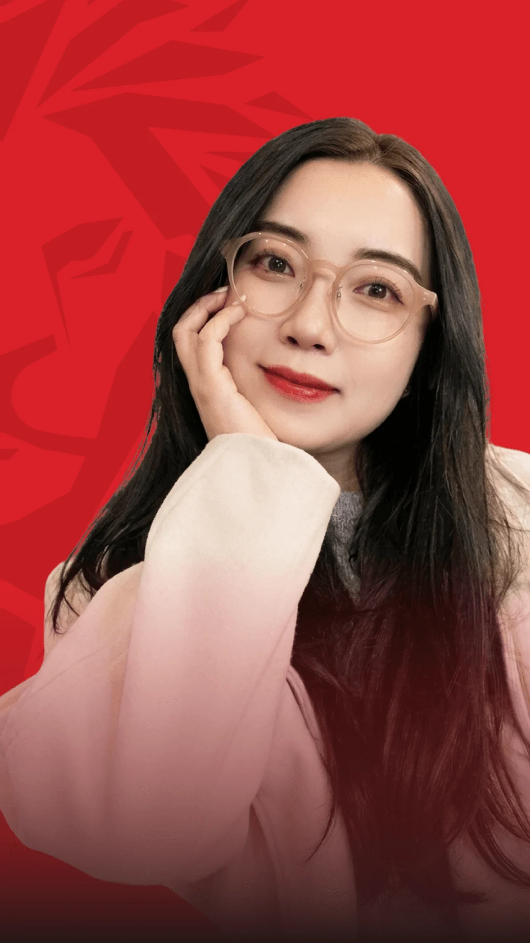 Portrait of a smiling female alum wearing round glasses, posing against a red background.