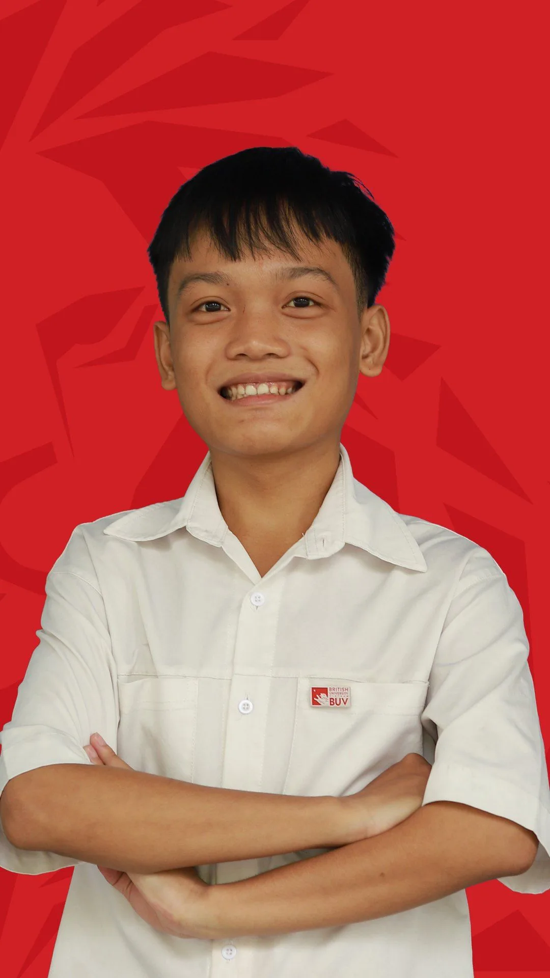 BUV alumnus Thanh Nhat smiling with arms crossed in a white university shirt against a red background.
