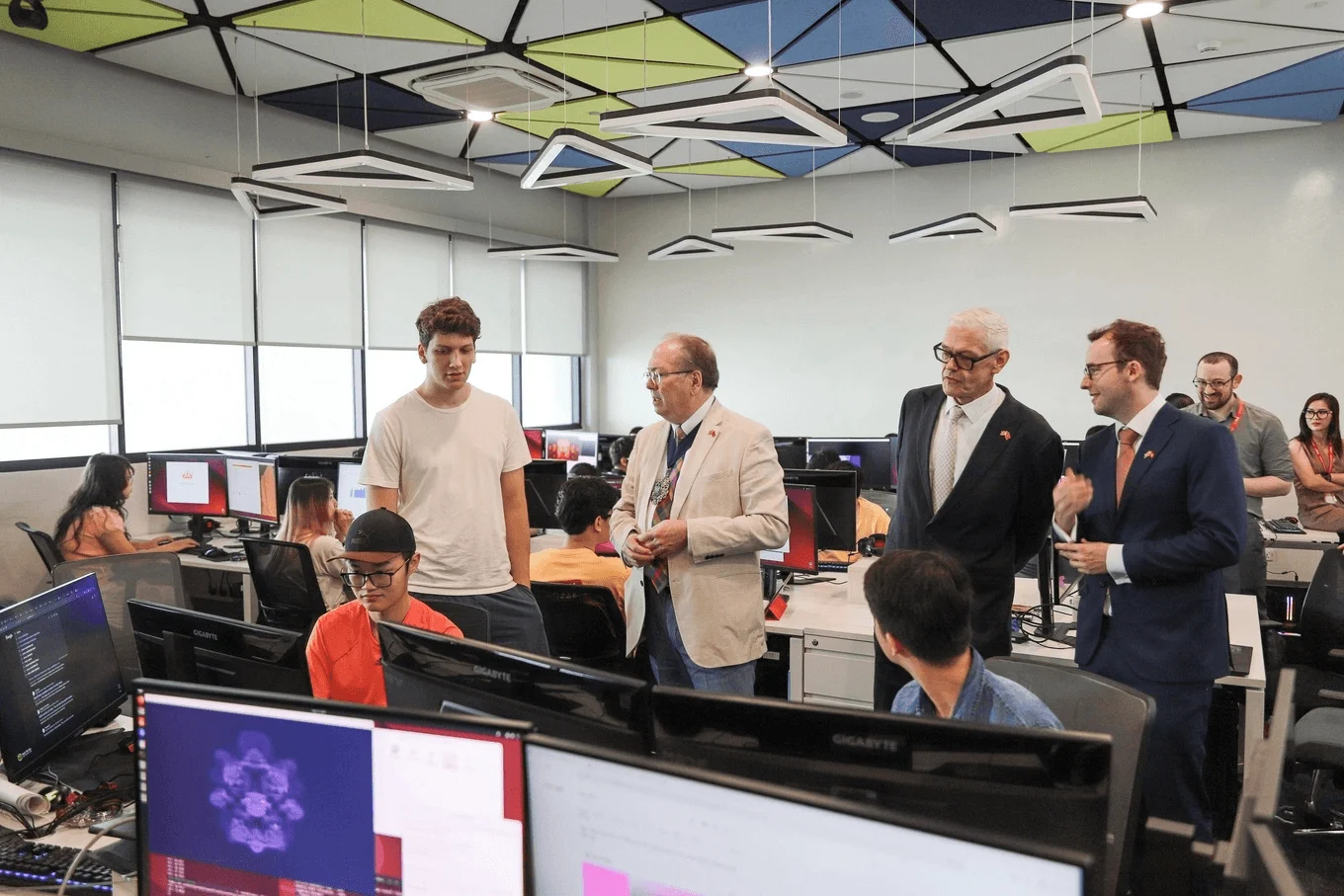 Officials and faculty members touring a computer lab and speaking with university students.