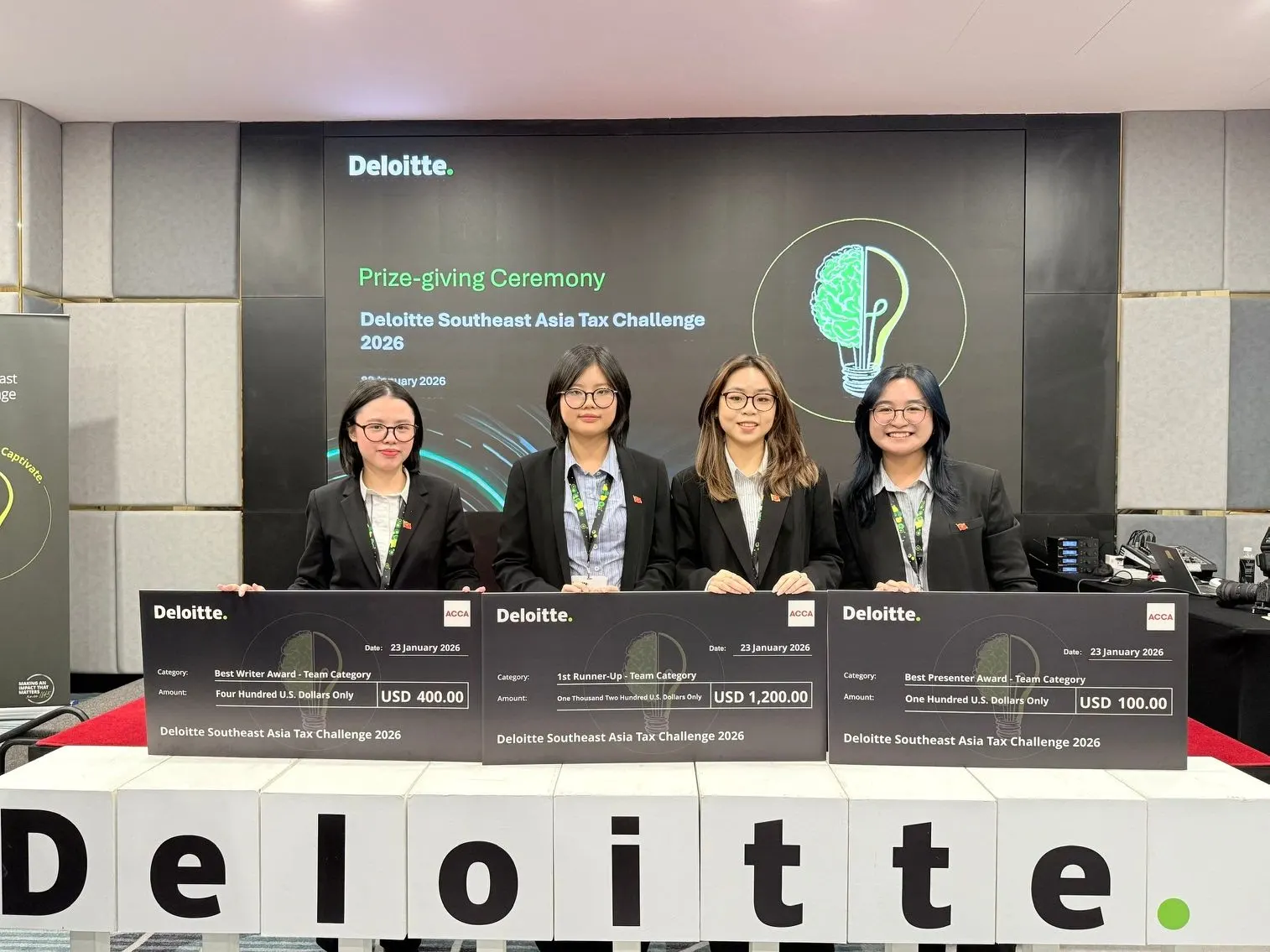 Four award recipients stand behind prize cheques at the Deloitte Southeast Asia Tax Challenge 2024 prize-giving ceremony.