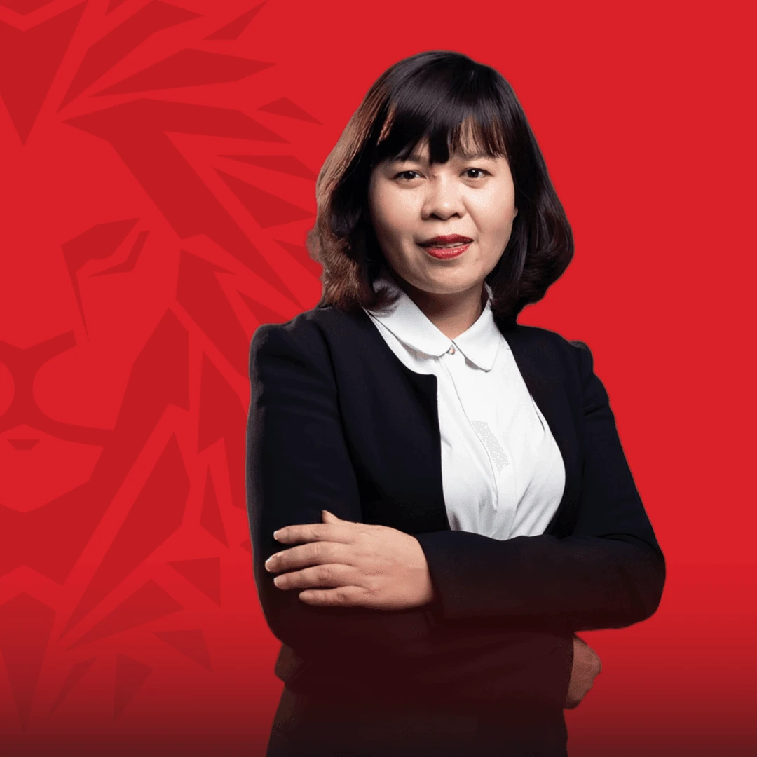 Portrait of a BUV alumna in a black blazer and white blouse, standing with arms crossed against a red graphic background.