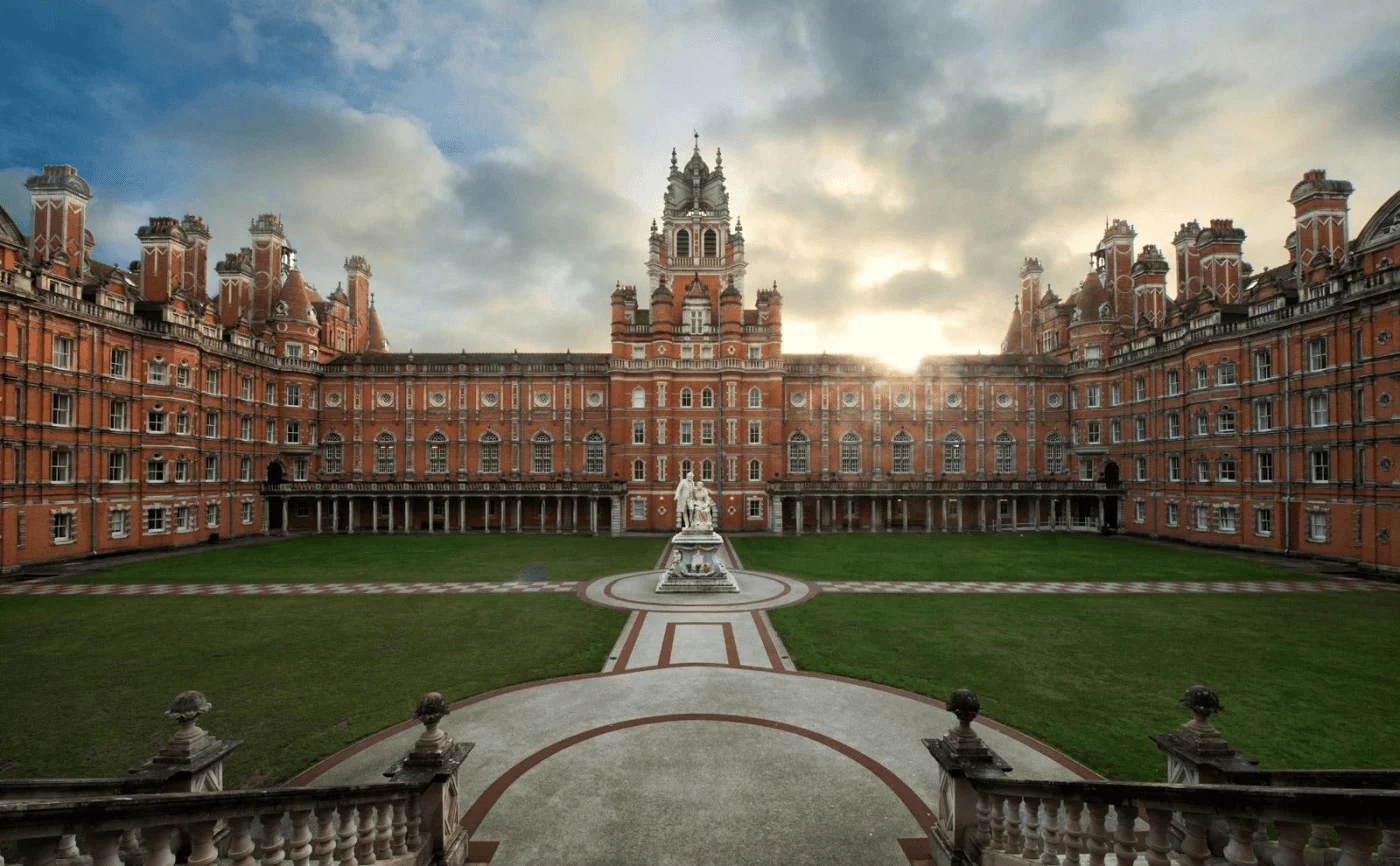 Historic red-brick university building surrounding a landscaped courtyard under a cloudy sky.