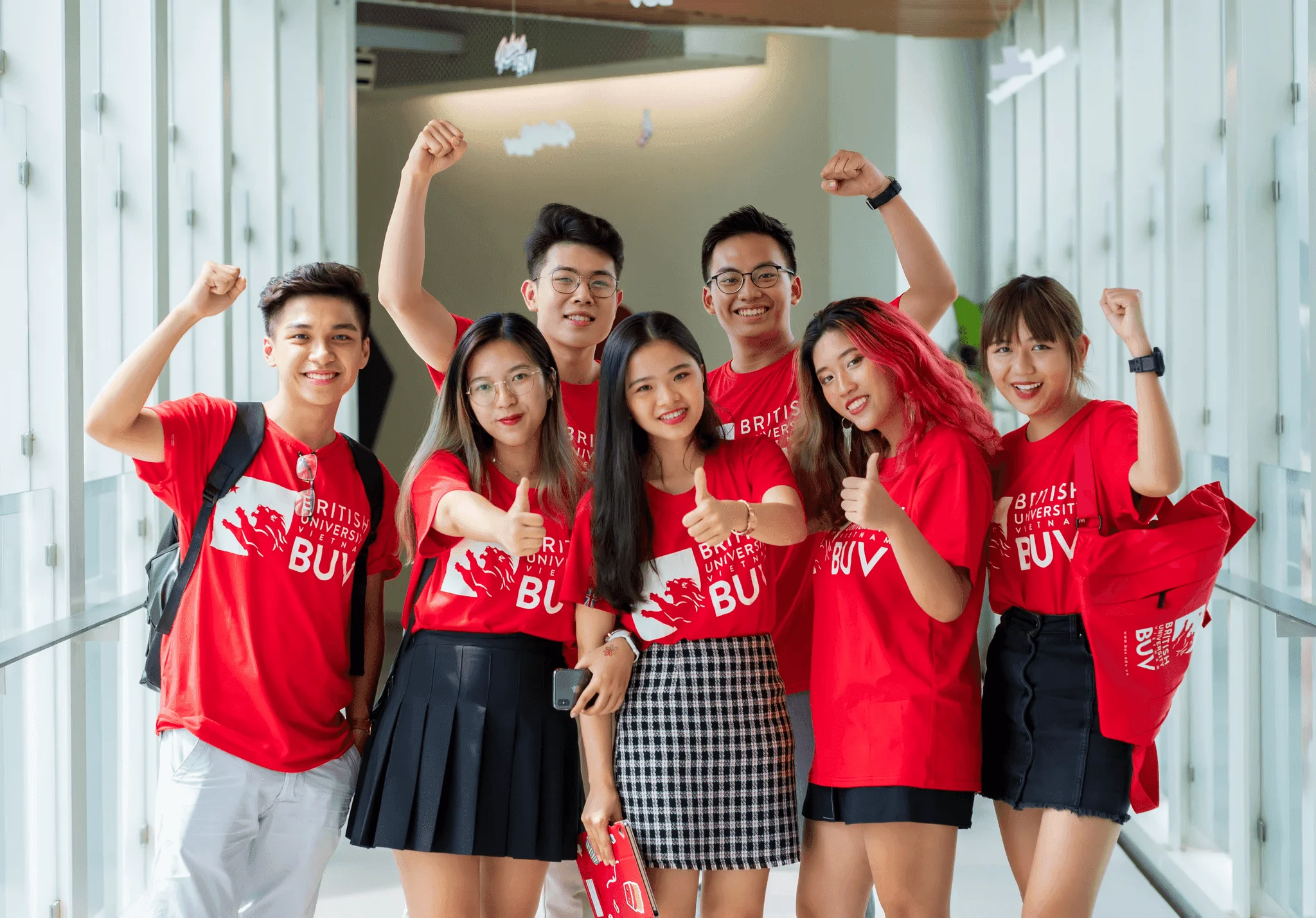 BUV students in red British University Vietnam shirts celebrating together in a campus hallway