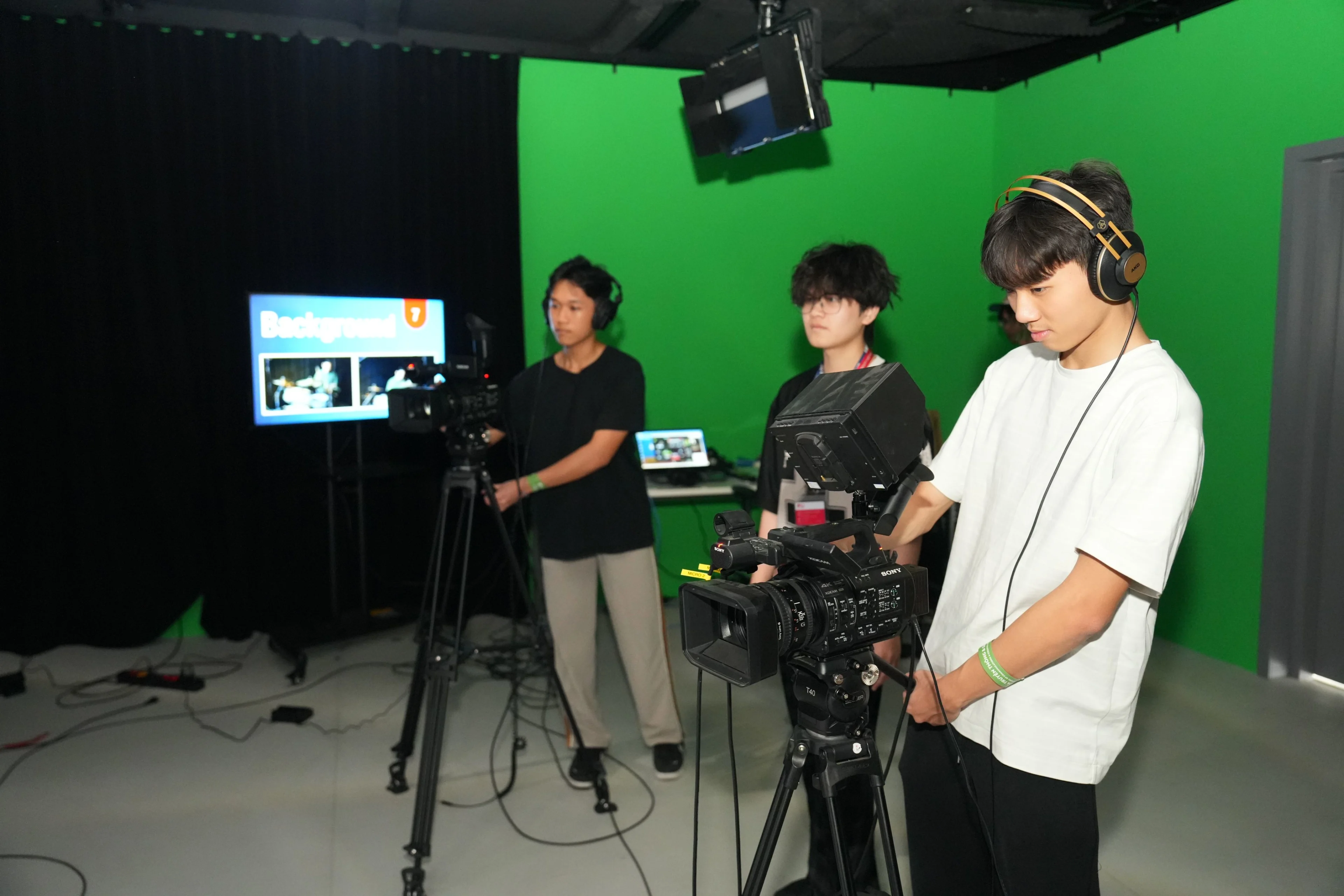 Sinh viên BUV thực hành quay phim với máy quay chuyên nghiệp trong studio phông xanh.