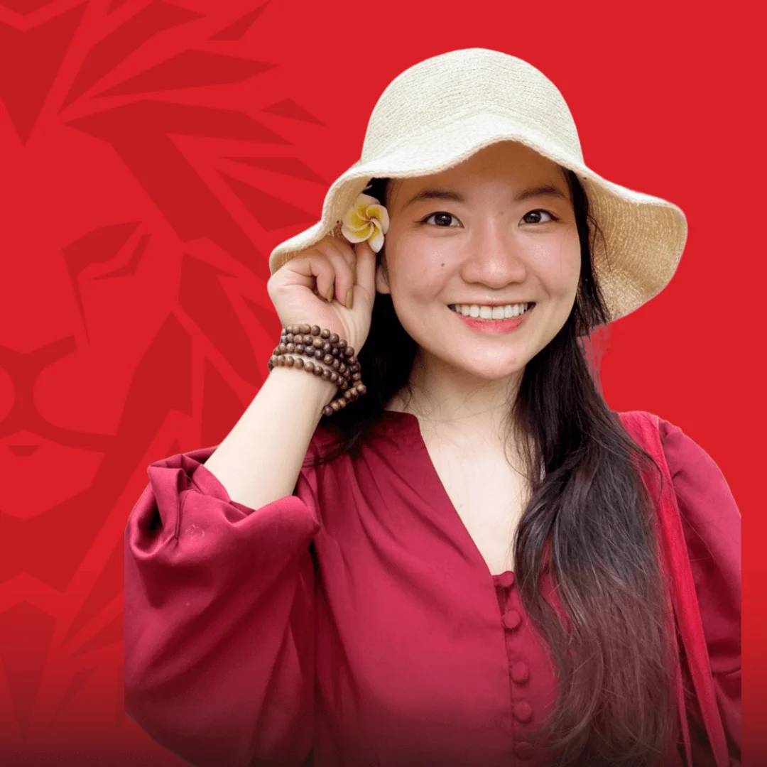 Cựu sinh viên BUV mỉm cười trong áo đỏ và mũ rộng vành trên nền đỏ thương hiệu համալսարանի