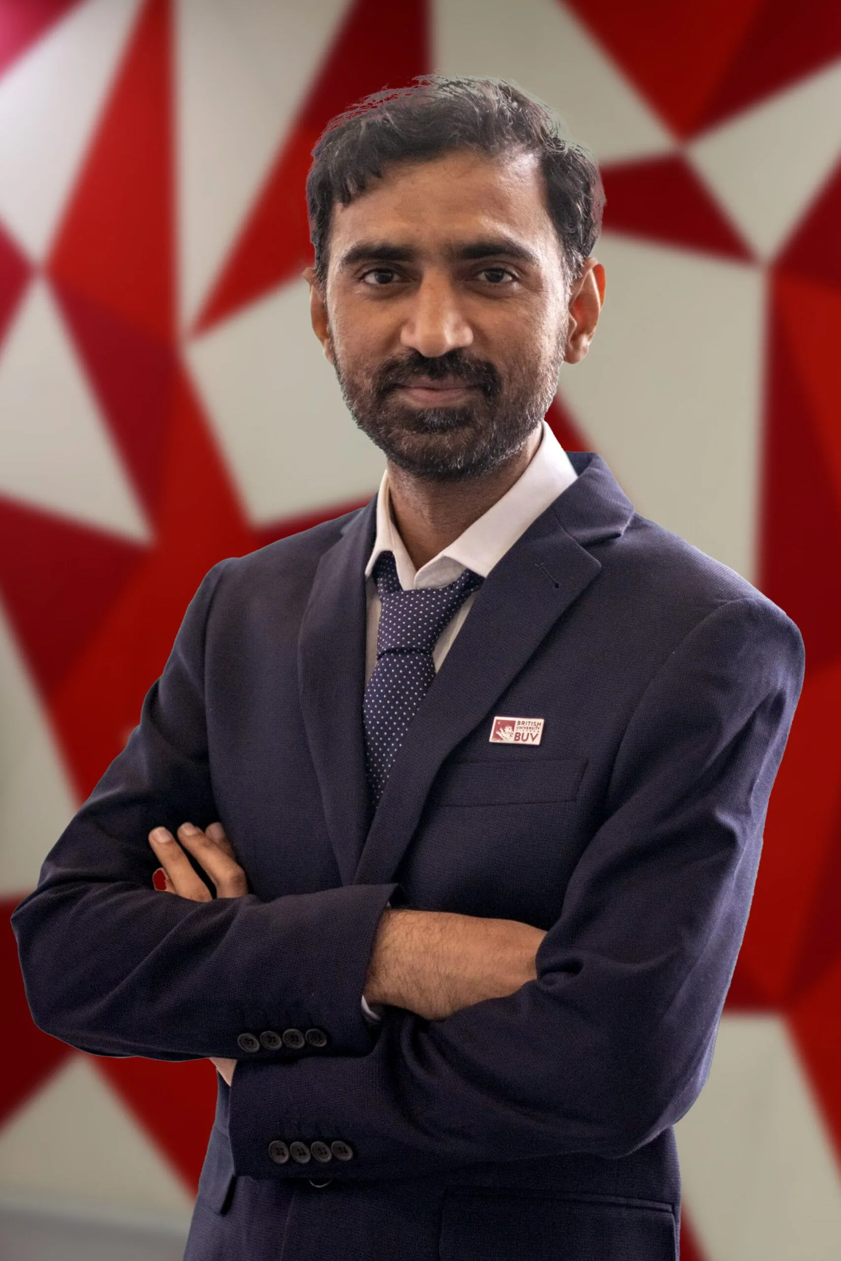 Dr Bilal Aslam in a navy suit wearing a British University Vietnam badge