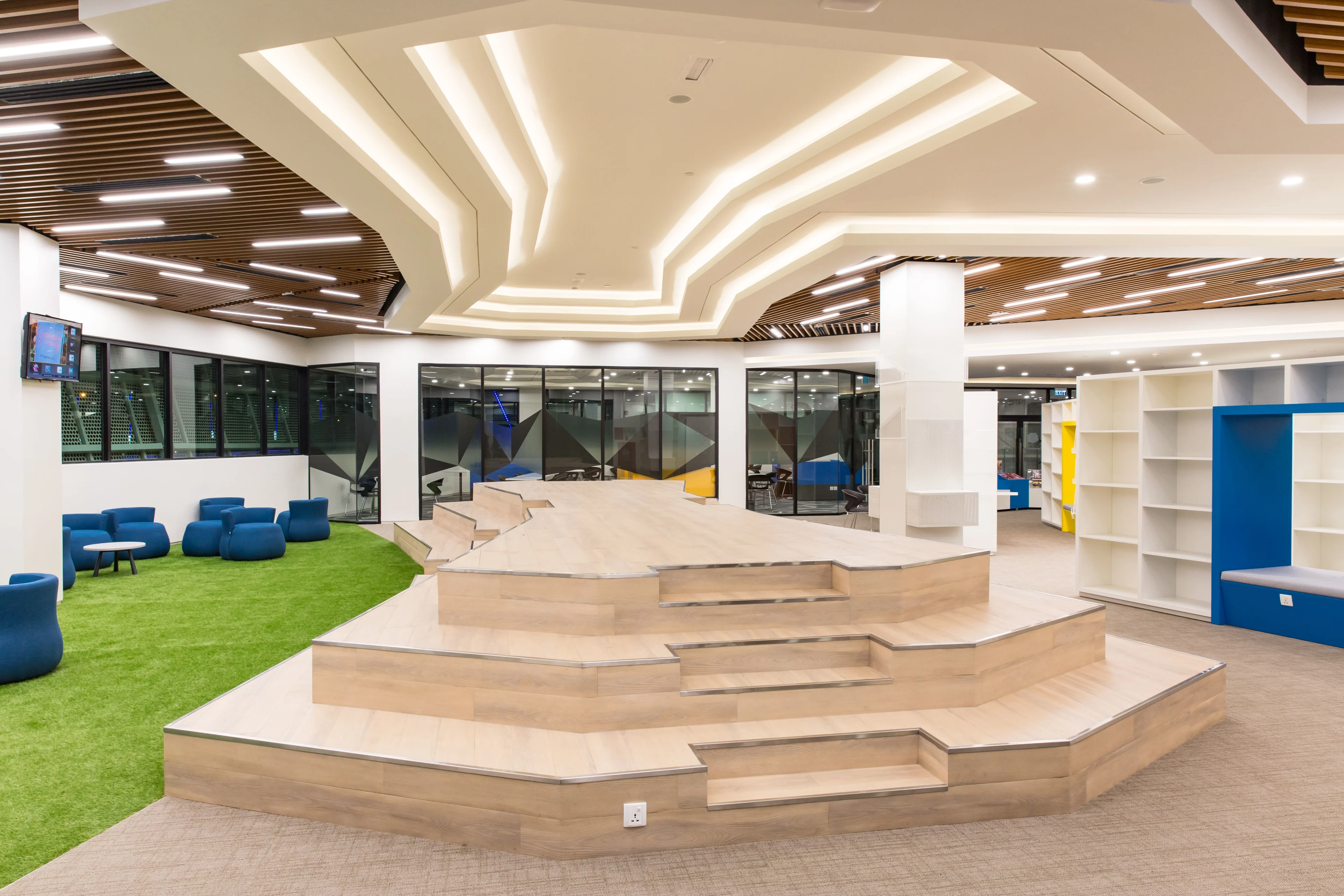 BUV modern student learning space with tiered wooden seating, blue lounge chairs and collaborative study areas